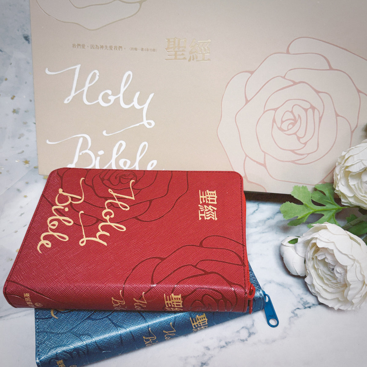 豪華款婚禮聖經禮盒情境展示,紅色與藍色 Holy Bible 拉鍊聖經疊放於玫瑰圖案禮盒前,呈現婚禮送禮氛圍