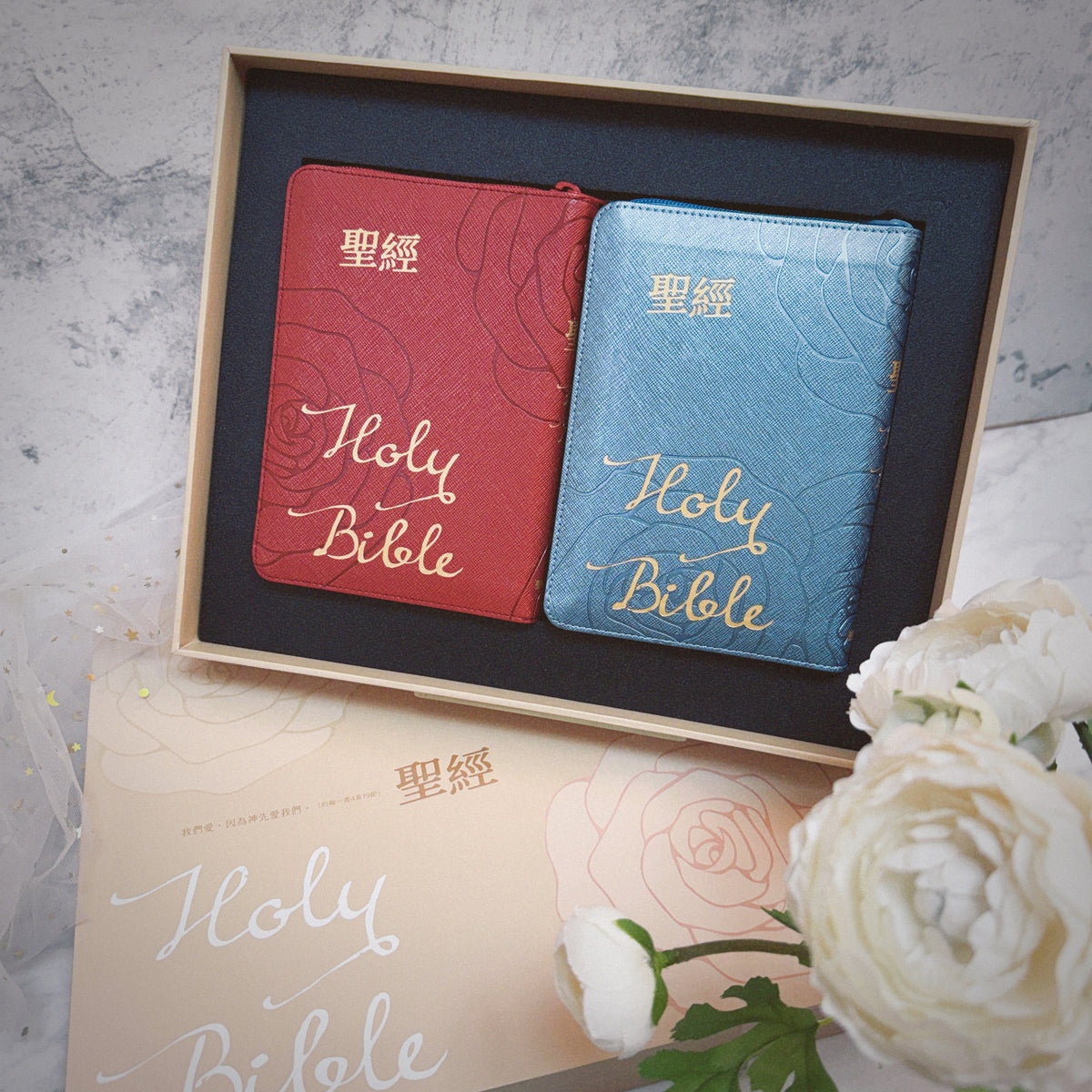 豪華款婚禮聖經禮盒內容物展示,紅色與藍色 Holy Bible 拉鍊聖經置於盒內,搭配玫瑰圖案外盒與白色花卉佈置