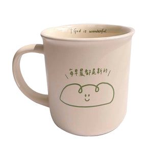 生命的糧陶瓷杯正面圖，淺米色陶瓷杯，杯身印有「每早晨都是新的」與綠色線條笑臉圖案，杯口內緣印有「+God is wonderful.」字樣。