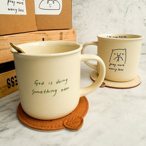 生命的糧陶瓷杯反面圖，淺米色陶瓷杯，杯身印有英文「God is doing something new.」字樣。