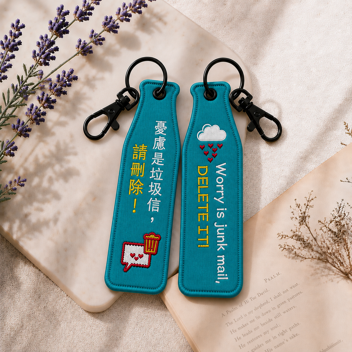 不憂慮綠色瓶安同行刺繡吊飾雙面展示，一面為中文「憂慮是垃圾信，請刪除！」字樣，另一面為英文 Worry is junk mail, DELETE IT! 字樣，搭配信件、垃圾桶與愛心雨雲插畫及黑色掛鉤。
