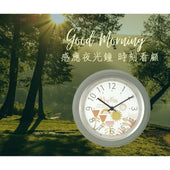時刻看顧感應夜光鐘晨光情境圖，森林湖畔背景展示圓形掛鐘與花卉鐘面設計。