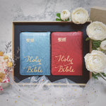 豪華款婚禮聖經禮盒商品展示，藍色與紅色 Holy Bible 拉鍊聖經並列於禮盒中，搭配白色花卉婚禮情境佈置